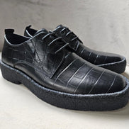 The Croc Derby with its black crocodile-embossed leather upper, three-eyelet lacing, and a thick, textured black and gum-colored crepe sole.