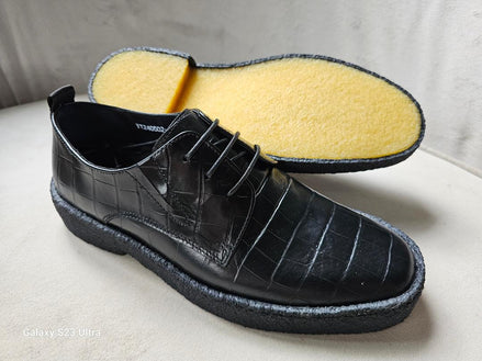 The Croc Derby featuring its black crocodile-embossed leather upper, three-eyelet lacing, and a thick, textured black and gum-colored crepe sole.