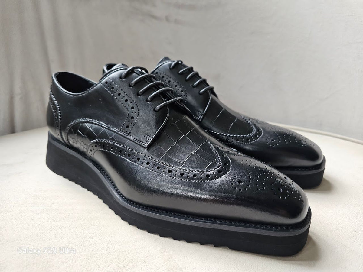 The Oba Wingtip with its multi-textured black leather design, croc-embossed vamps, and intricate wingtip brogue detailing.