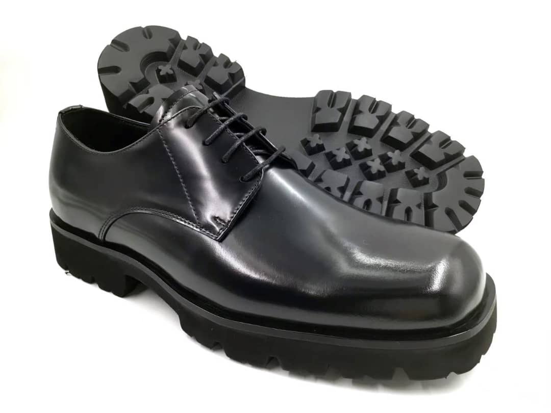 The Titan Lug Derby with its high-shine polished black leather, distinctive square-toe shape, and a thick, heavy-duty black lug sole.
