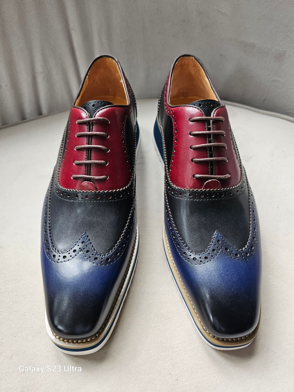 This hybrid dress shoe combines a traditional wingtip brogue upper with a contemporary white ripple sole. Featuring a bold midnight navy and rich burgundy leather construction