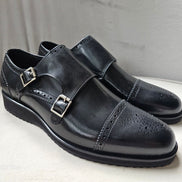 The Zaki Monk with its polished black leather finish, intricate brogue detailing on the cap toe, and signature dual buckle closures.