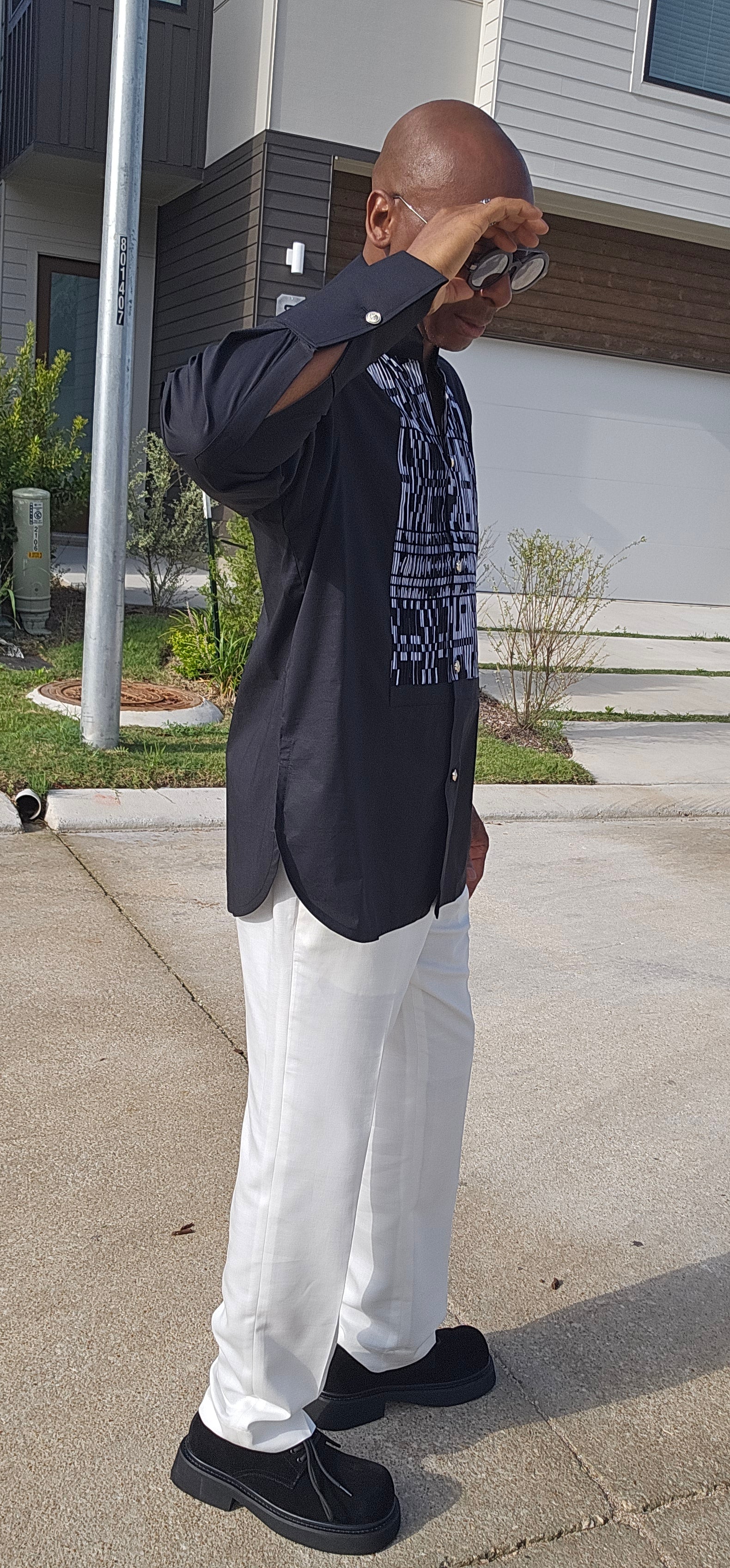 Top featuring a long-sleeved black tunic design with a geometric black-and-white print front panel and a high mandarin collar.
