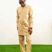Traditional African outfit featuring a tan long-sleeved tunic with a round neckline, center-front button detailing, and matching structured trousers. Front View