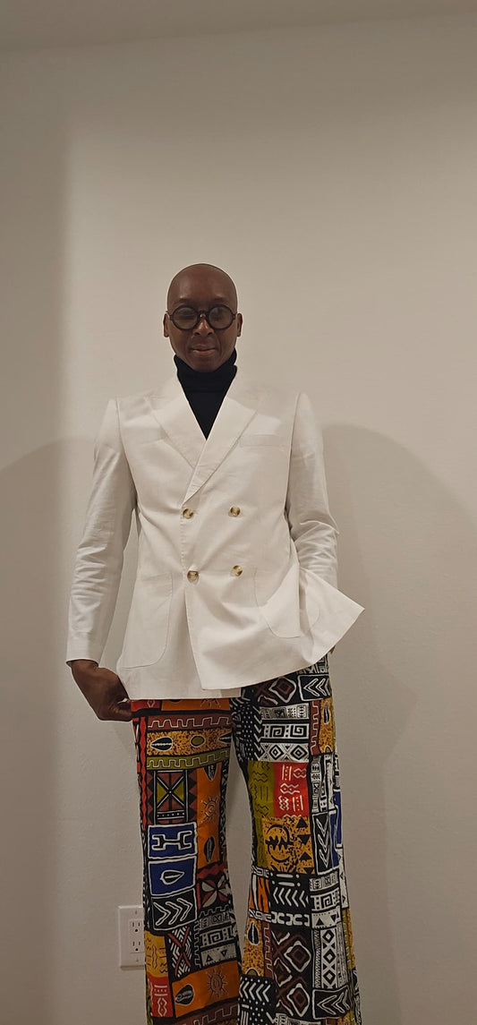 Trousers featuring a vibrant, multi-colored patchwork Ankara print with geometric and tribal motifs in a dramatic wide-leg silhouette.