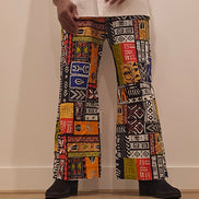 Trousers featuring a vibrant, multi-colored patchwork Ankara print with geometric and tribal motifs in a dramatic wide-leg silhouette.