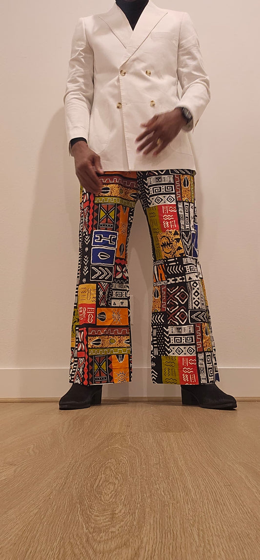 Trousers featuring a vibrant, multi-colored patchwork Ankara print with geometric and tribal motifs in a dramatic wide-leg silhouette.