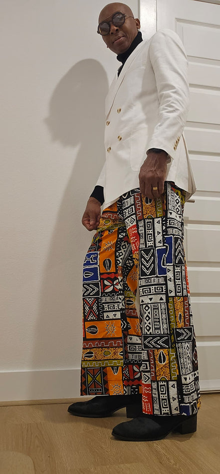 Trousers featuring a vibrant, multi-colored patchwork Ankara print with geometric and tribal motifs in a dramatic wide-leg silhouette.
