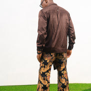 Two-Piece Set   featuring a chocolate brown long-sleeve button-down shirt with metallic hardware and ornate gold and navy patterned palazzo trousers.
Back Posing 
