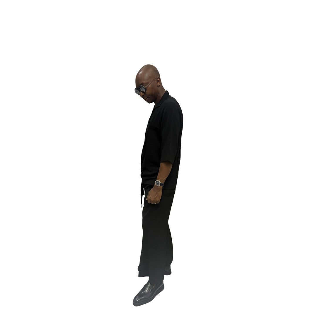 Two-Piece Set featuring a sleek black short-sleeved tunic shirt with a structured polo-style collar, subtle chest-panel stitching, and coordinating wide-leg trousers
