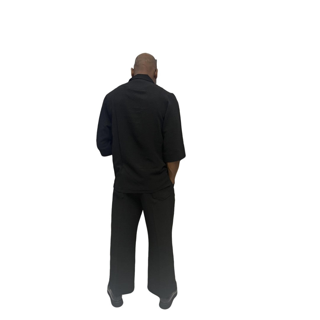 Two-Piece Set featuring a sleek black short-sleeved tunic shirt with a structured polo-style collar, subtle chest-panel stitching, and coordinating wide-leg trousers