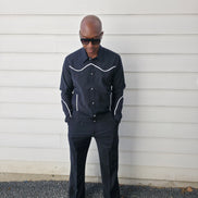 Two-piece black virgin wool suit featuring white contrast piping on the jacket chest and sleeves with matching tailored trousers.