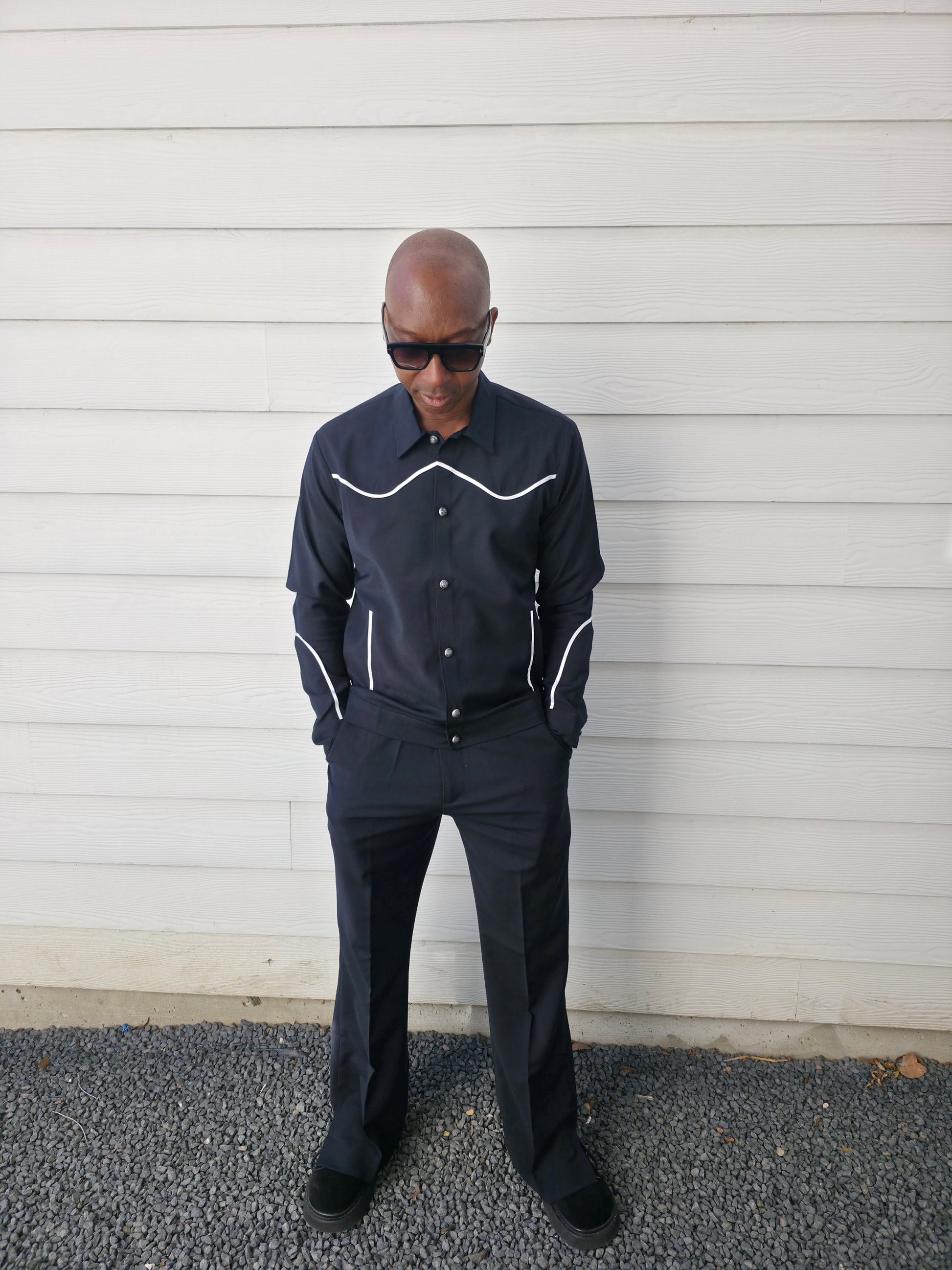 Two-piece black virgin wool suit featuring white contrast piping on the jacket chest and sleeves with matching tailored trousers.