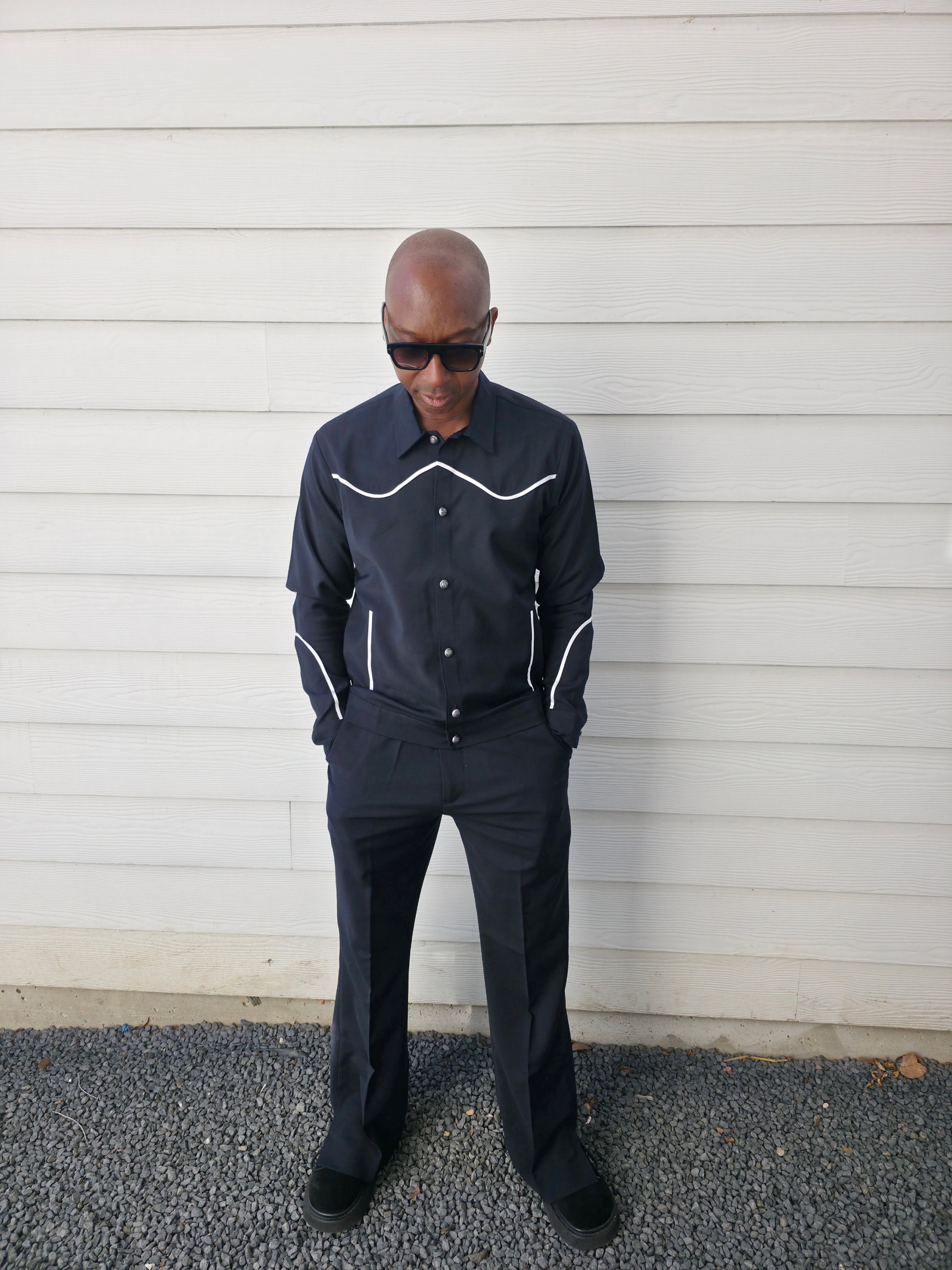 Two-piece black virgin wool suit featuring white contrast piping on the jacket chest and sleeves with matching tailored trousers.