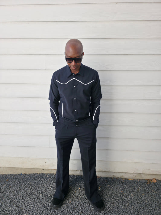Two-piece black virgin wool suit featuring white contrast piping on the jacket chest and sleeves with matching tailored trousers.
