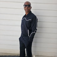Two-piece black virgin wool suit featuring white contrast piping on the jacket chest and sleeves with matching tailored trousers.