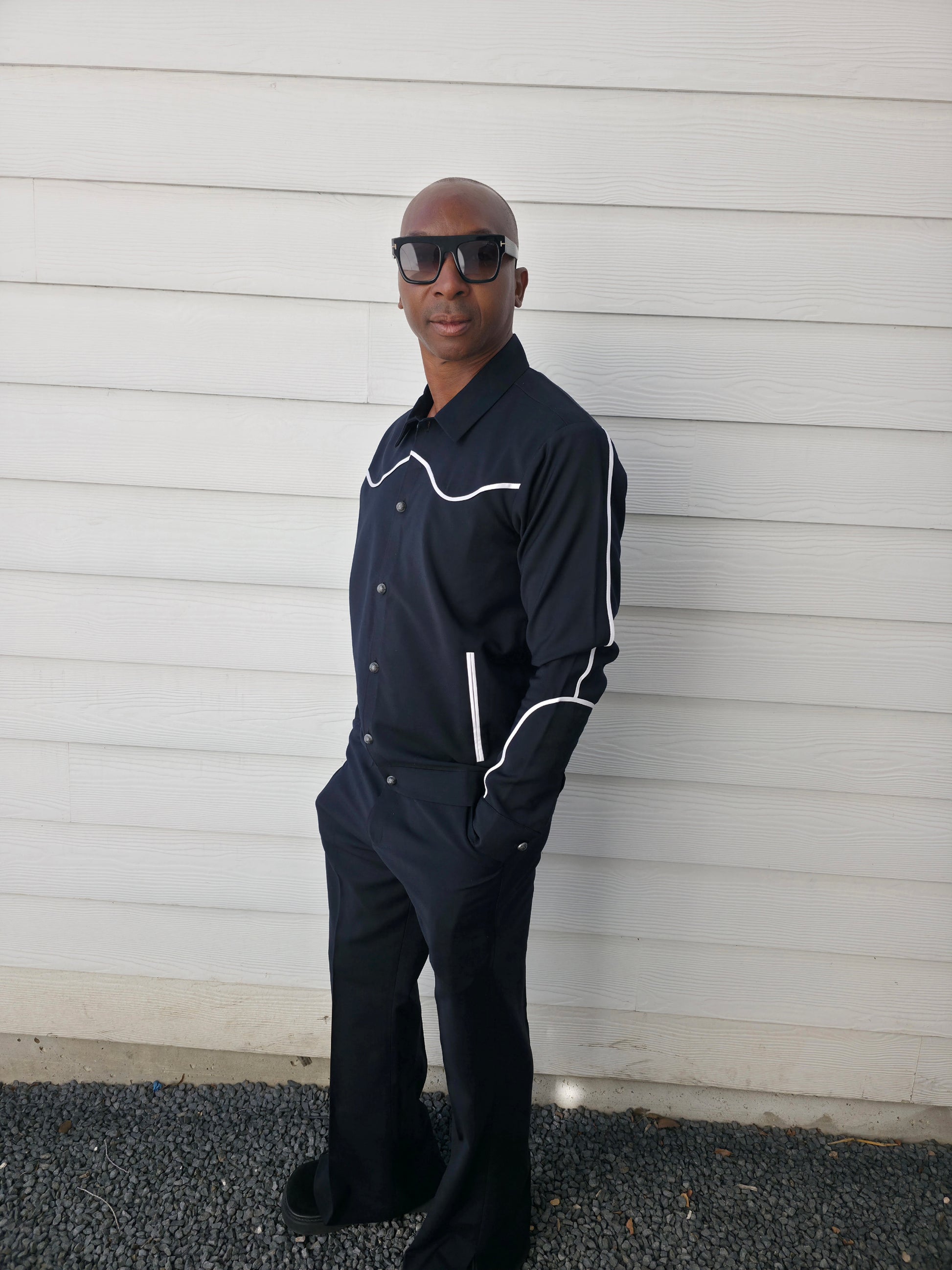 Two-piece black virgin wool suit featuring white contrast piping on the jacket chest and sleeves with matching tailored trousers.