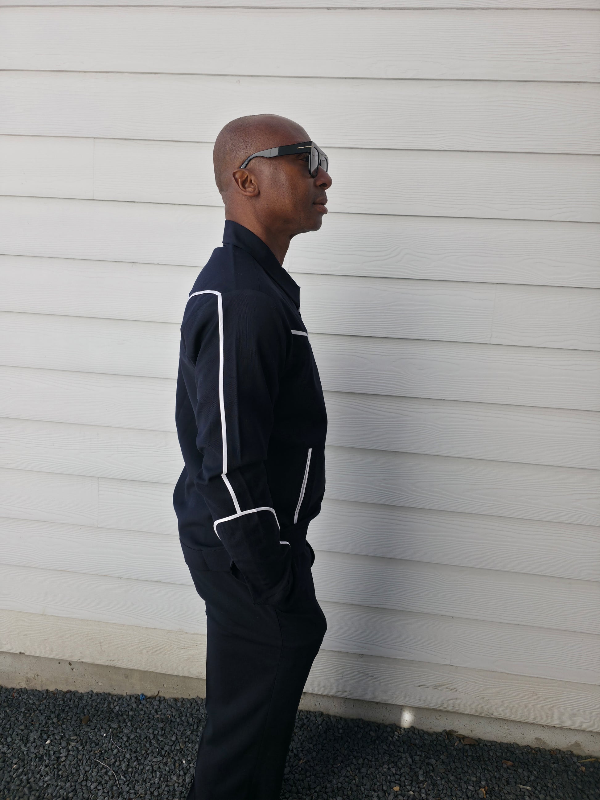 Two-piece black virgin wool suit featuring white contrast piping on the jacket chest and sleeves with matching tailored trousers.