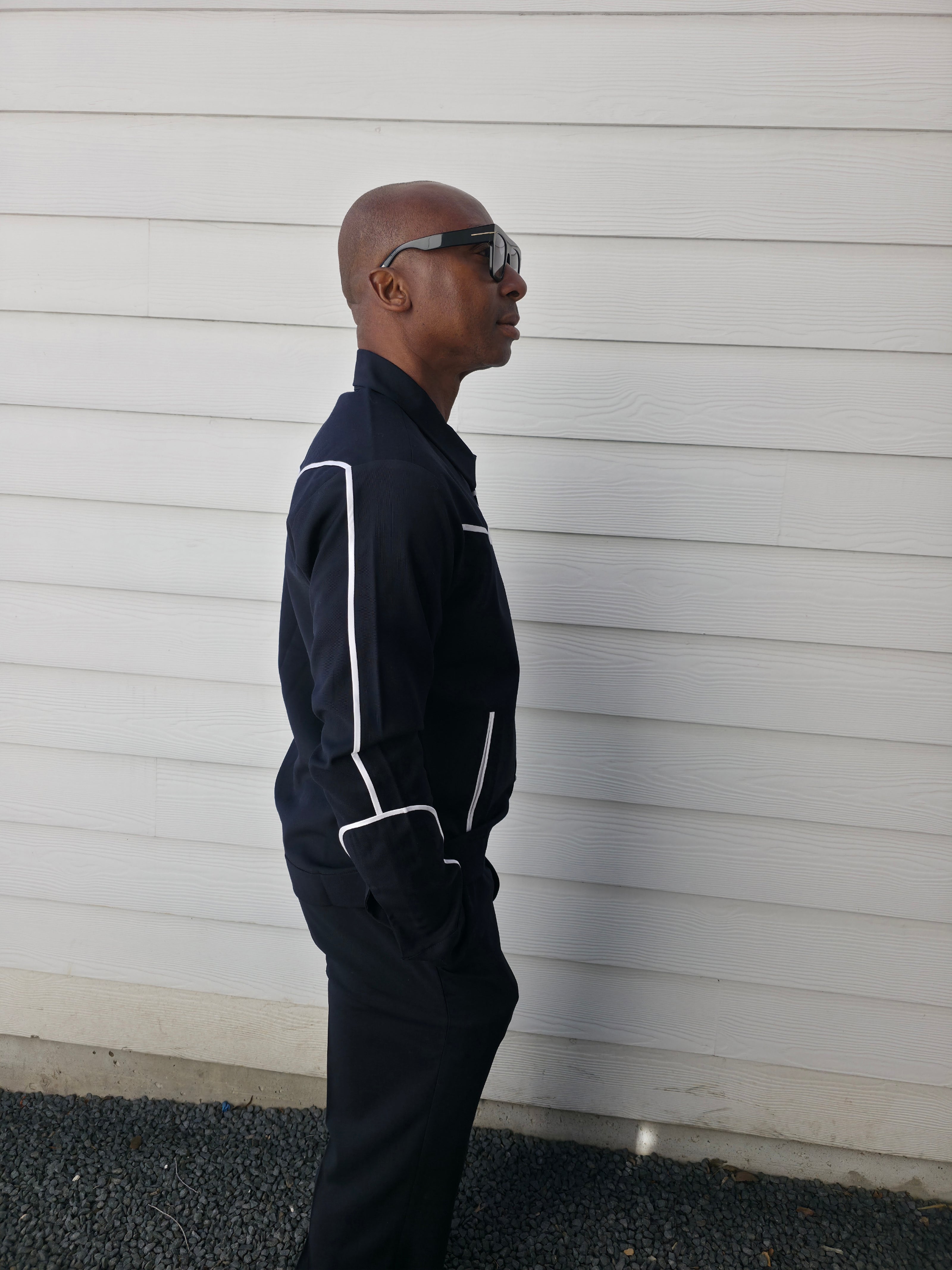 Two-piece black virgin wool suit featuring white contrast piping on the jacket chest and sleeves with matching tailored trousers.