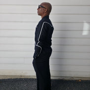 Two-piece black virgin wool suit featuring white contrast piping on the jacket chest and sleeves with matching tailored trousers.