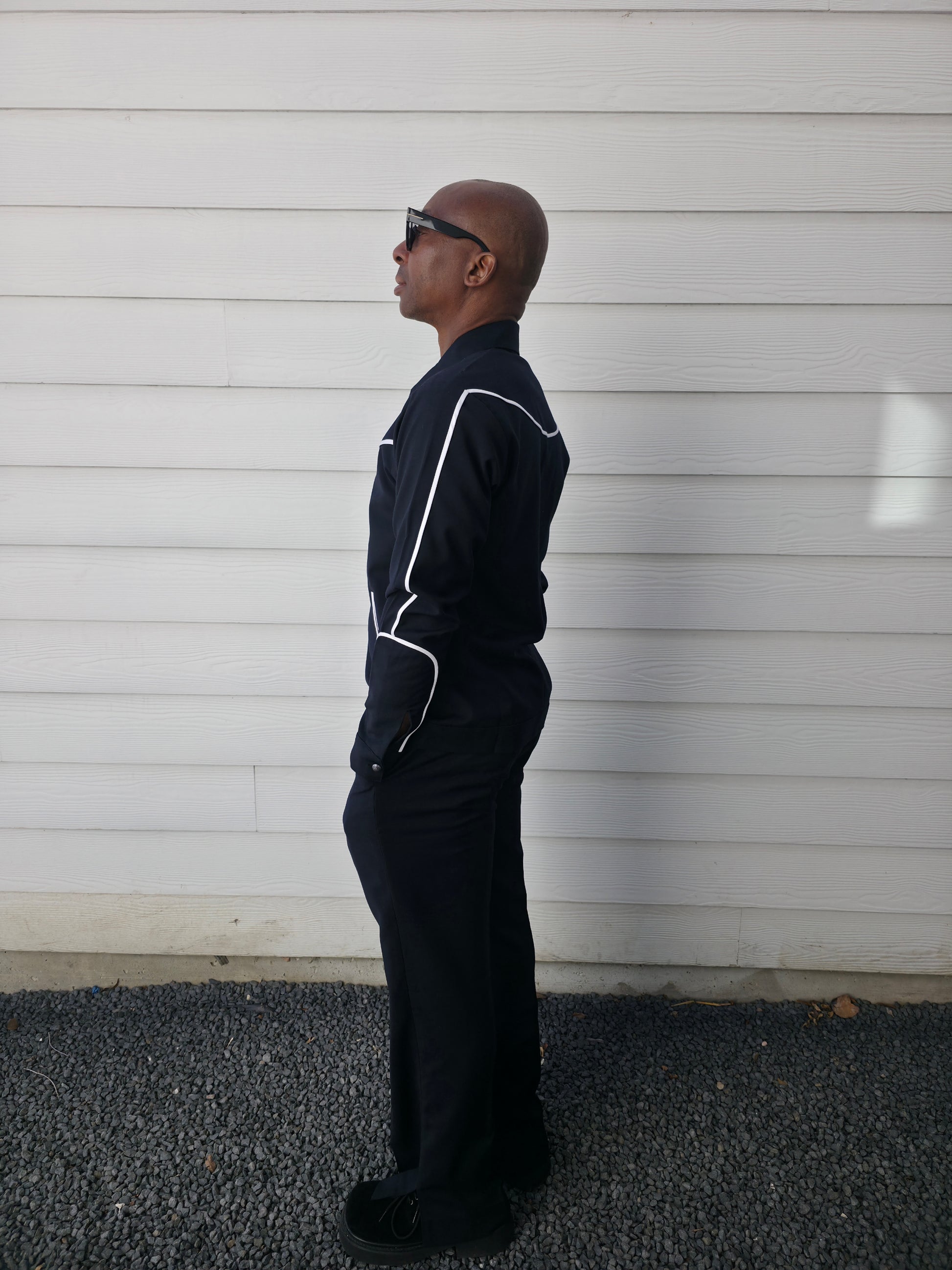 Two-piece black virgin wool suit featuring white contrast piping on the jacket chest and sleeves with matching tailored trousers.