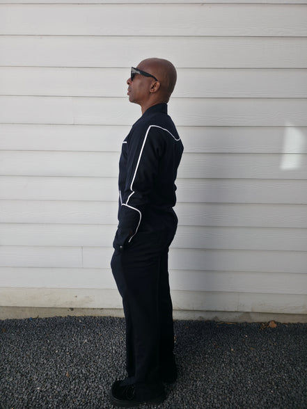 Two-piece black virgin wool suit featuring white contrast piping on the jacket chest and sleeves with matching tailored trousers.