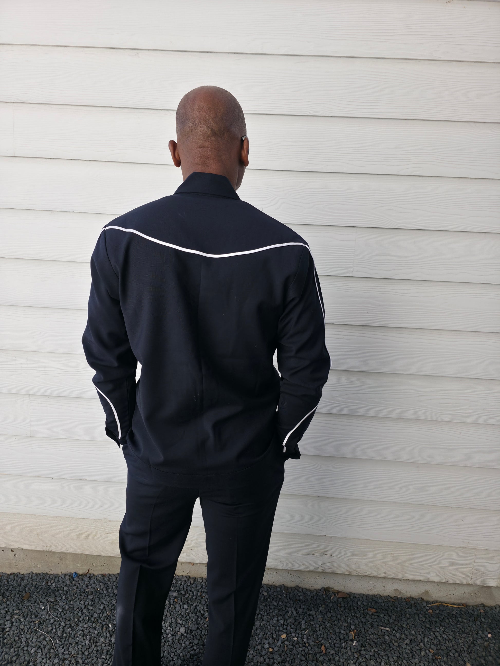 Two-piece black virgin wool suit featuring white contrast piping on the jacket chest and sleeves with matching tailored trousers.
