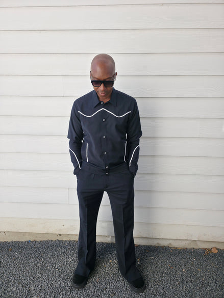Two-piece black virgin wool suit featuring white contrast piping on the jacket chest and sleeves with matching tailored trousers.