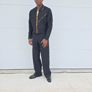 Two-Piece Set featuring a black virgin wool cropped zip-up jacket and wide-leg trousers accented by thin red, yellow, and green Ankara patterned piping.