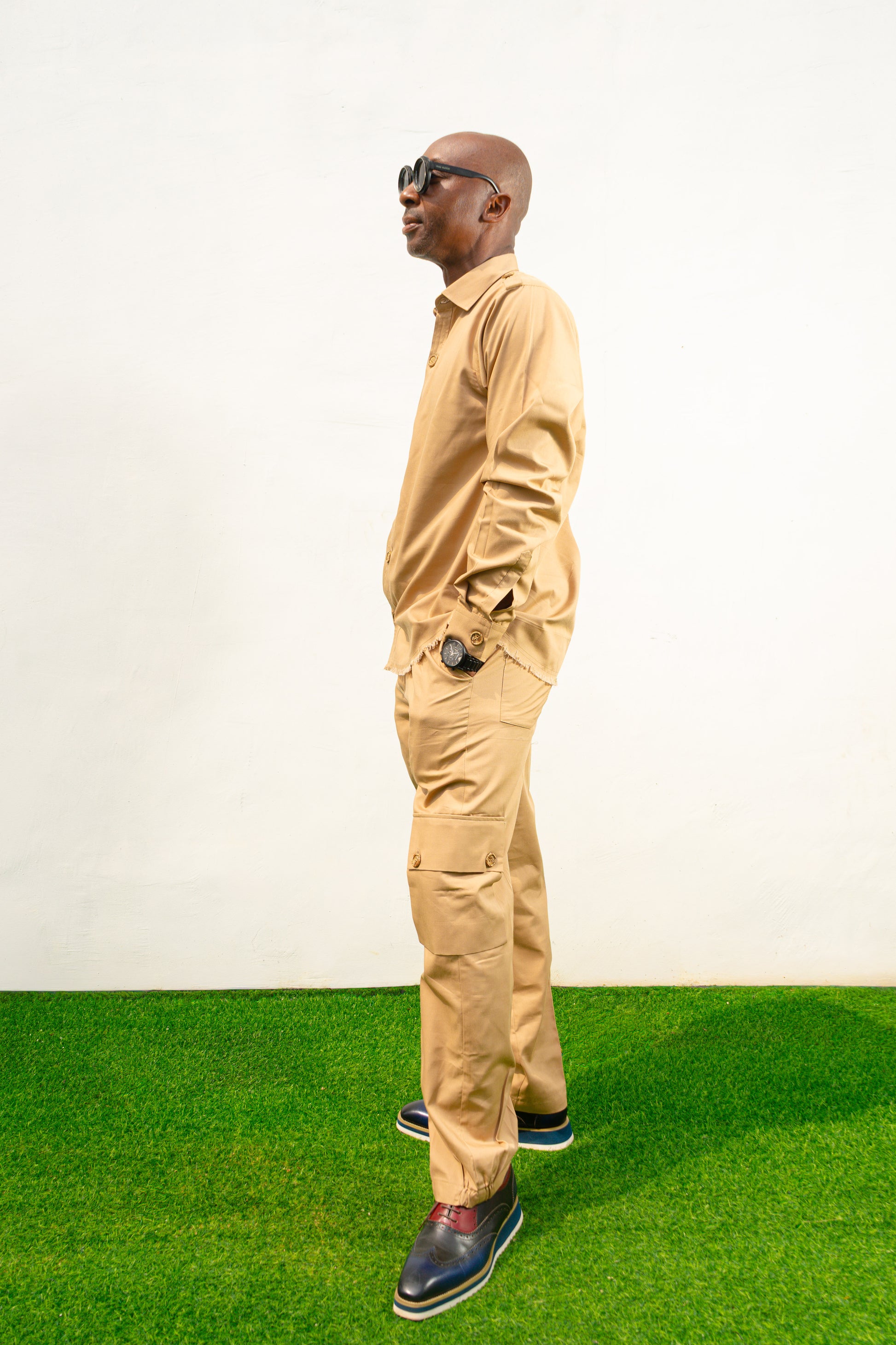 Two-Piece Set featuring a beige long-sleeved button-down shirt with shoulder epaulets and matching cargo-style trousers with side pockets. 