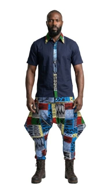 Man wearing a dark blue shirt and colorful patterned pants on a white background