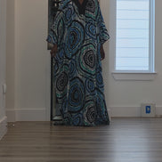 Patterned Boubou Kaftan featuring a blue and turquoise concentric circular print, a solid black V-neckline, and a voluminous silhouette.