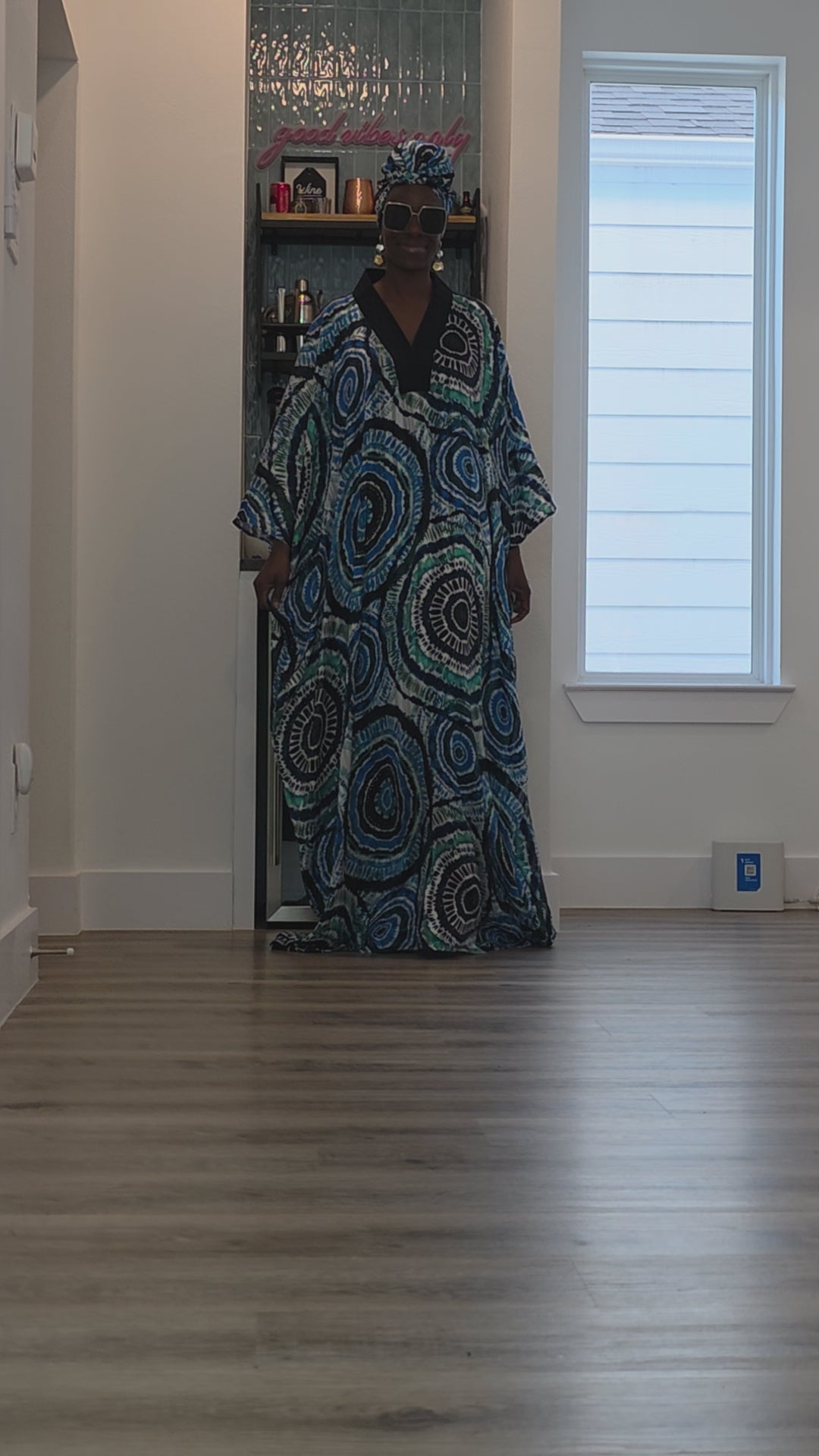 Patterned Boubou Kaftan featuring a blue and turquoise concentric circular print, a solid black V-neckline, and a voluminous silhouette.