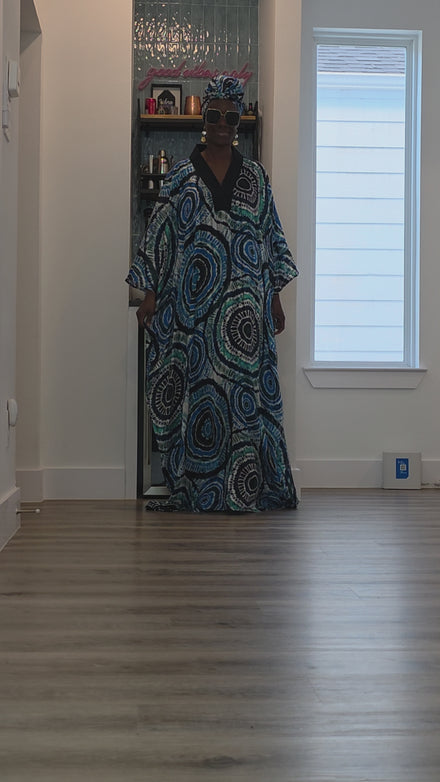 Patterned Boubou Kaftan featuring a blue and turquoise concentric circular print, a solid black V-neckline, and a voluminous silhouette.